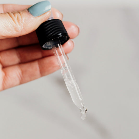 Hand holding a glass serum dropper