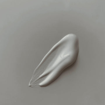 A swipe of white cream on a soft grey surface