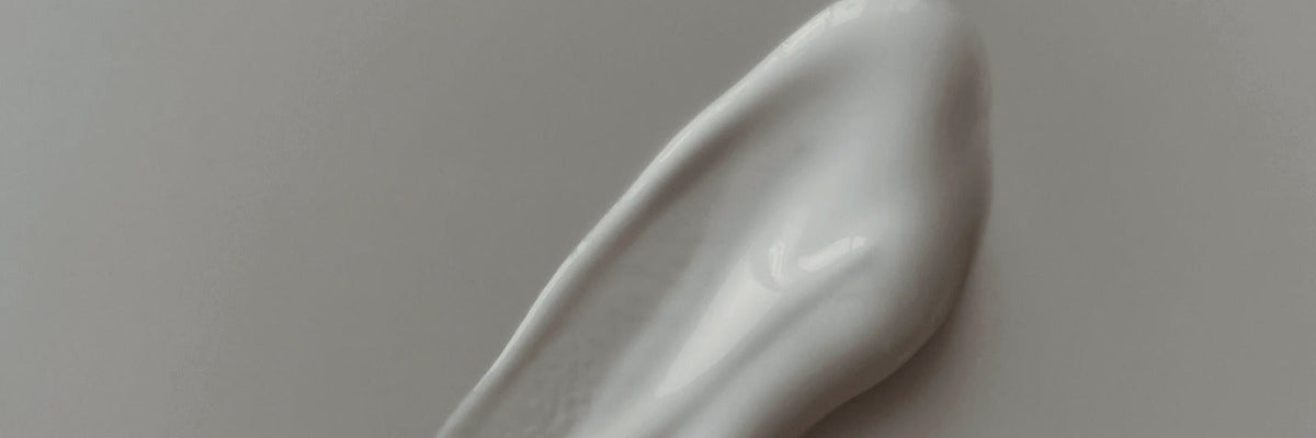 A swipe of white cream on a soft grey surface