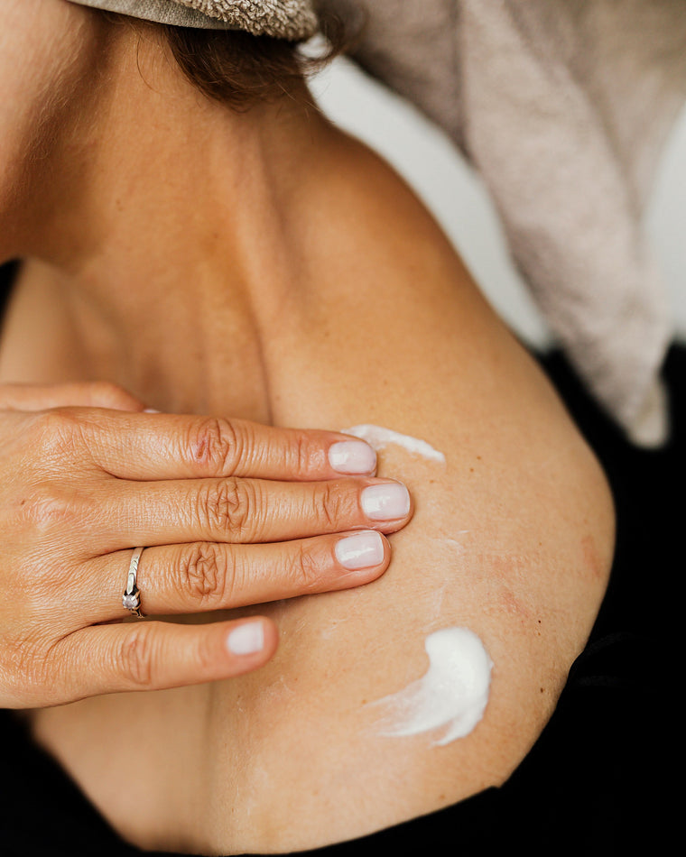 Hands applying cream to a shoulder